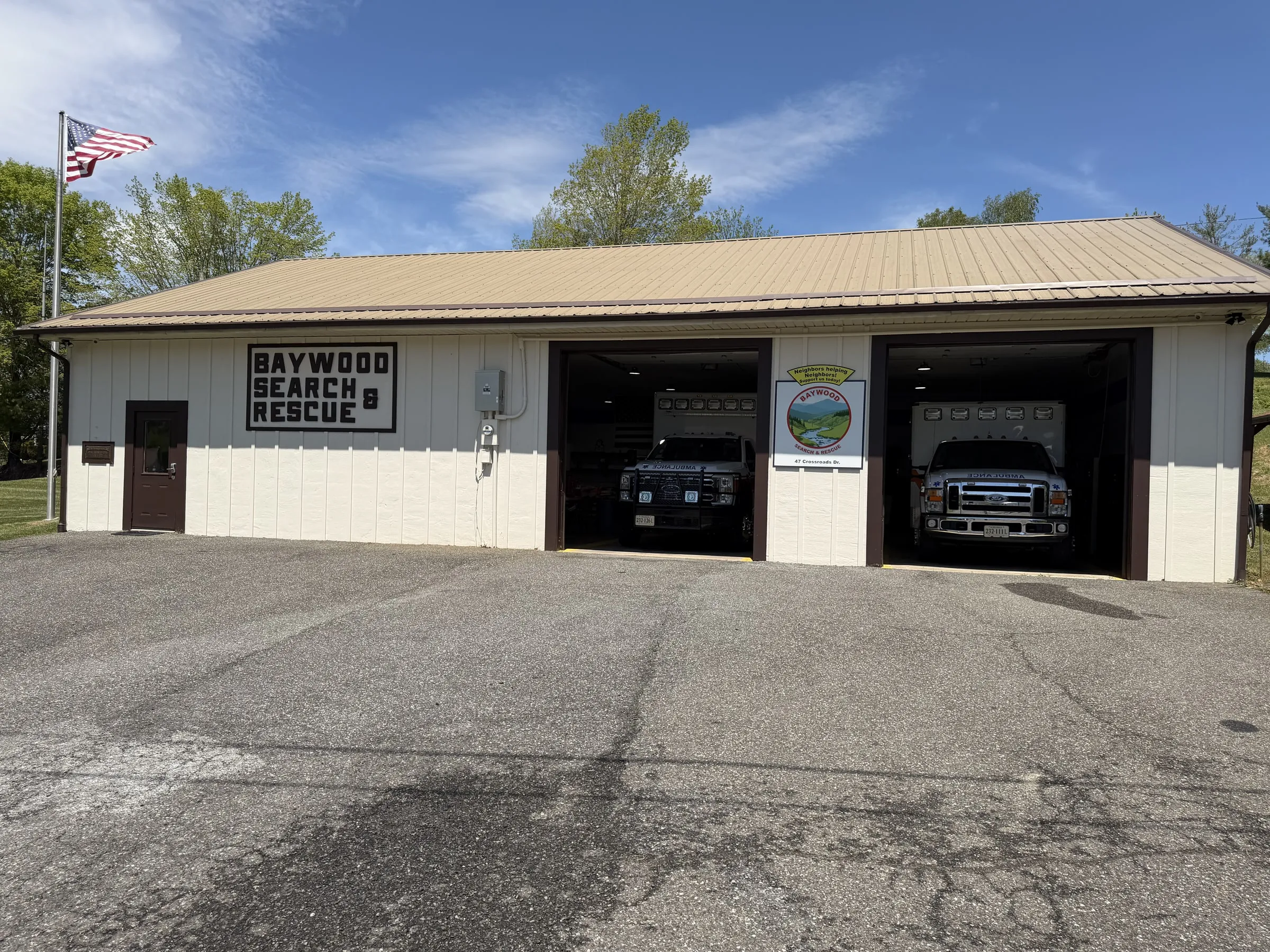 Baywood Search and Rescue station with both bay doors open and two ALS ambulances inside, U.S. flag flying overhead