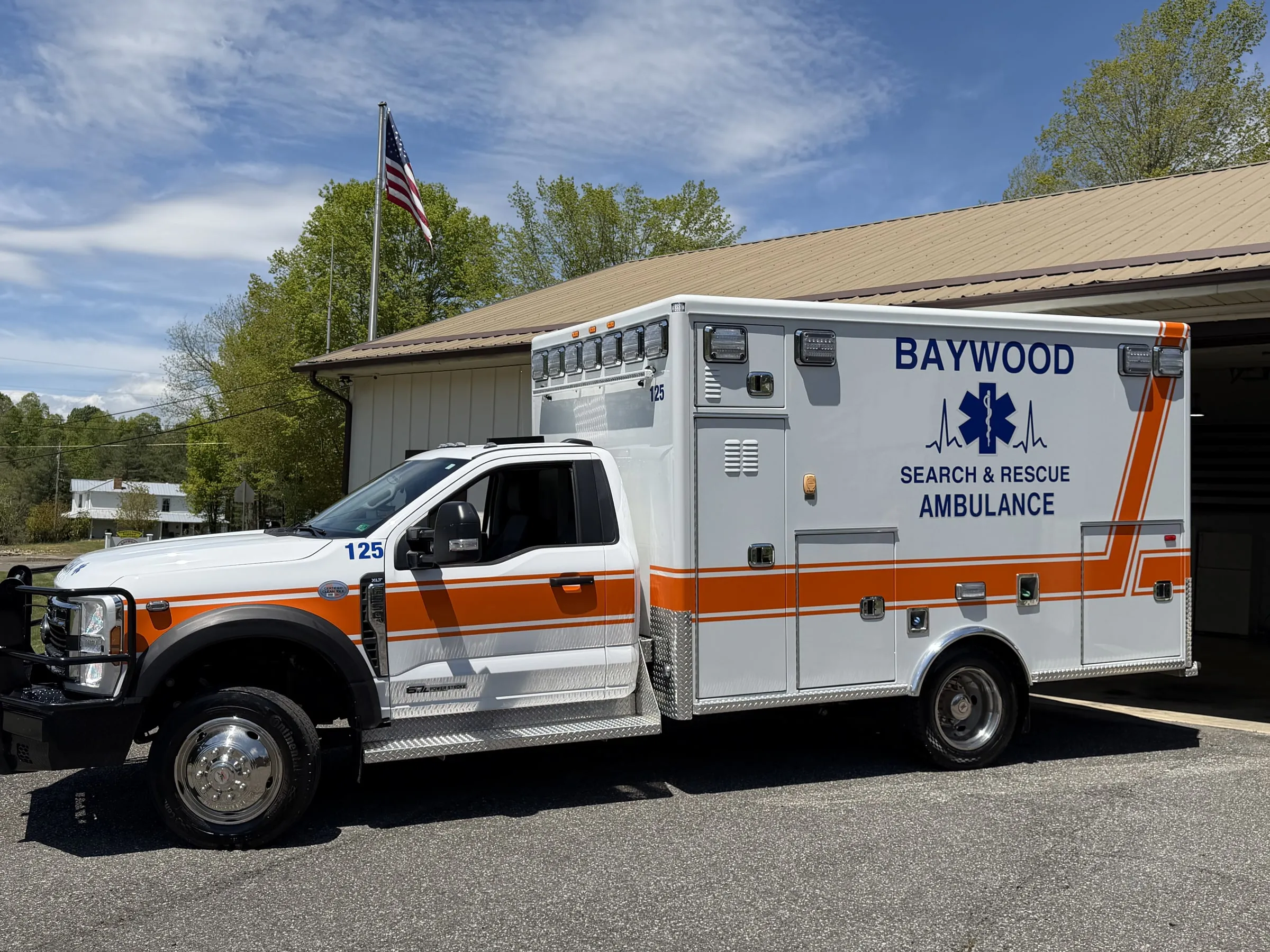 Driver-side profile of Baywood's ALS ambulance with U.S. flag flying behind